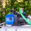 cuve-ibc-blanc-avec-pompe-220V-1000L-nettoye-palette-acier-plastique-vue-de-cote-pompe-avec-tuyau-de-sortie.webp