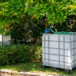 cuve-ibc-blanc-avec-pompe-220V-1000L-nettoye-palette-acier-plastique-vue-de-droite-dans-environnement-de-jardin.webp