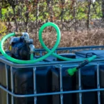 cuve-ibc-noir-avec-pompe-sur-batterie-1000L-renouvele-palette-acier-plastique-vue-de-cote-avec-tuyau-sortant.webp