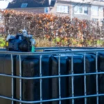 cuve-ibc-noir-avec-pompe-sur-batterie-1000L-renouvele-palette-acier-plastique-vue-de-devant-cote-sans-tuyau-sortant.webp